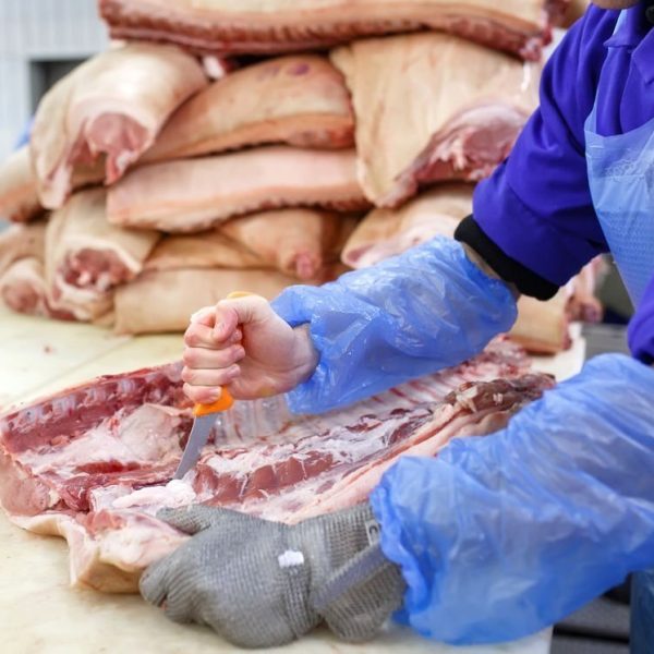 Cutting meat in slaughterhouse. The meat and sausage factory
